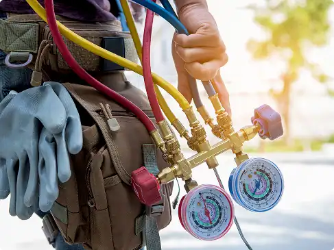 A professional McGee HVAC technician, wearing a tool belt, expertly holds a manifold gauge set with red and blue pressure dials.