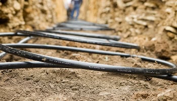 Black piping coiled in a narrow trench excavated by the McGee team.